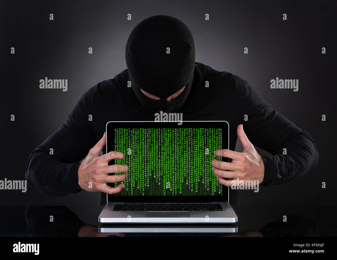 Hacker in einer Lava, die in der Dunkelheit steht, stehlen heimlich Daten von einem Laptop oder setzen Spyware in eine Online-Sicherheits- und Risikokonce ein Stockfoto