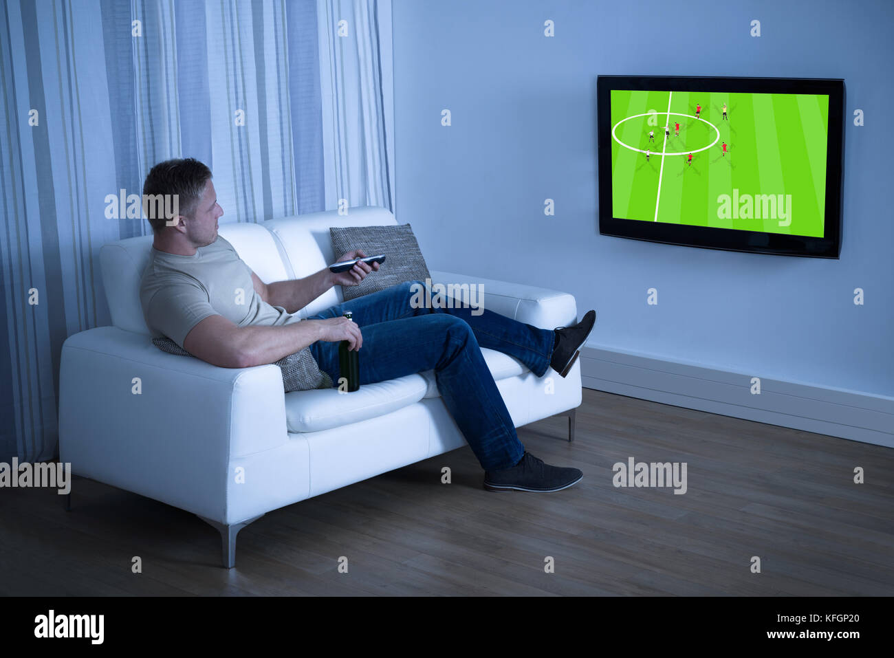 Mann sitzt auf der Couch ansehen Fußball-Spiel zu Hause im Fernsehen Stockfoto