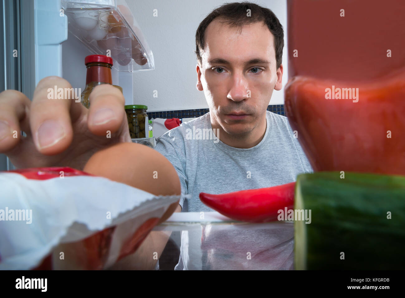 Nahaufnahme eines Mannes, der ein Ei aus dem Kühlschrank nimmt Stockfoto