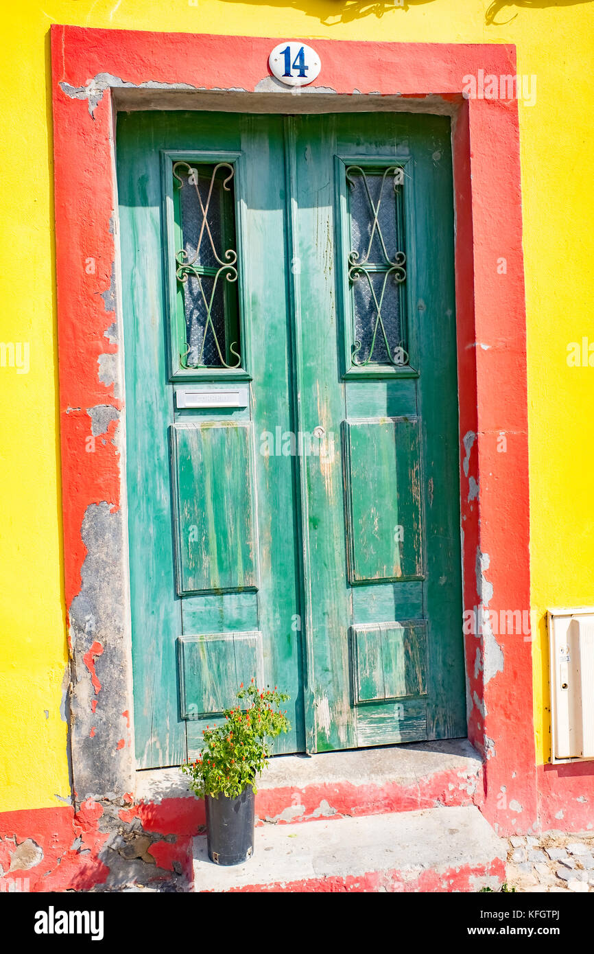 Verwitterten grünen Tür mit leuchtend roten Surround in gelbe Wand Stockfoto