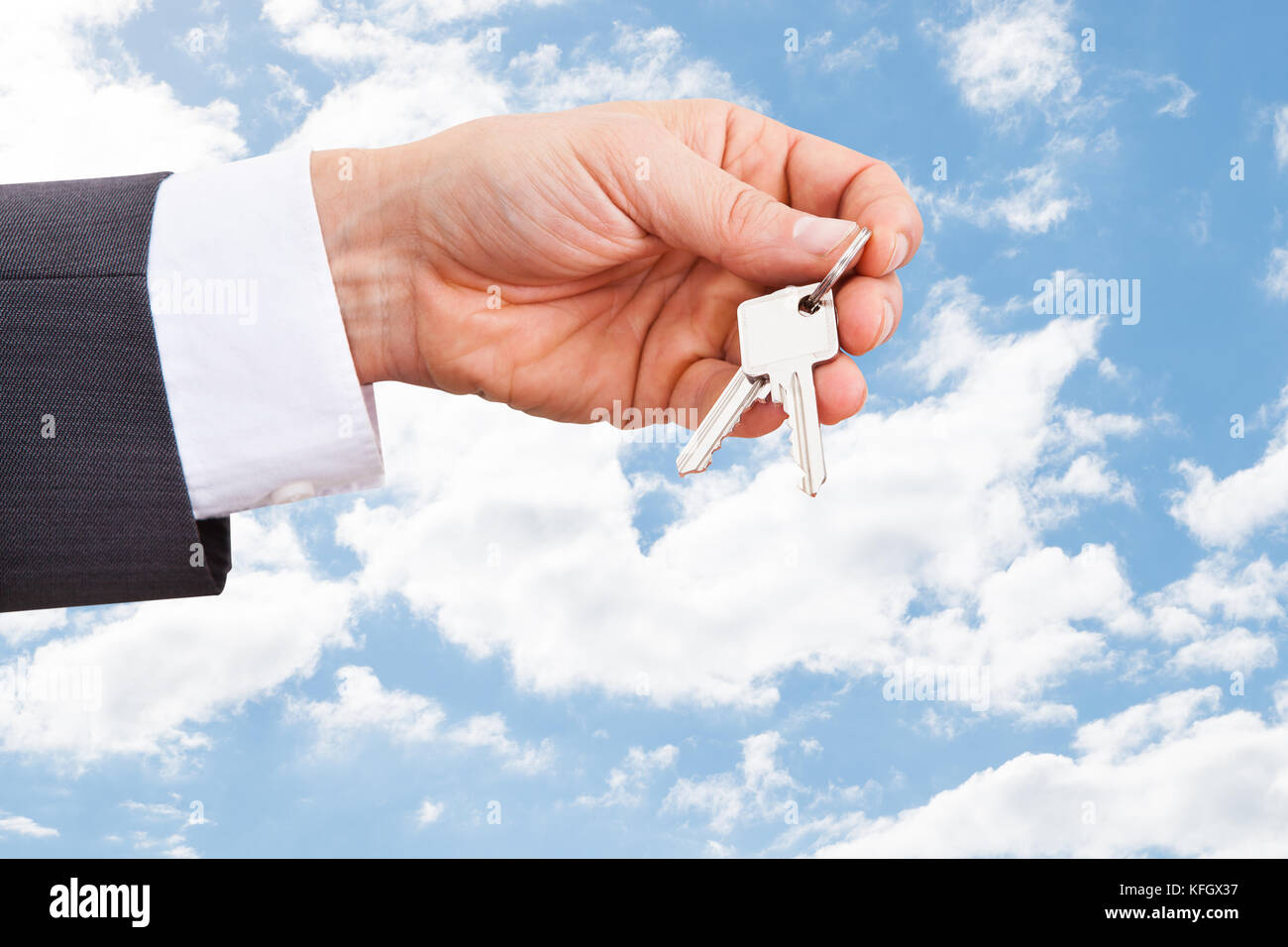Nahaufnahme einer Hand, die Schlüssel des real estate agent gegen bewölkter Himmel Stockfoto