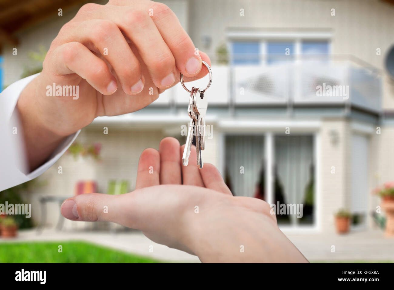 7/8 Image der Immobilienmakler, die Schlüssel zum Eigentümer gegen neues Haus Stockfoto
