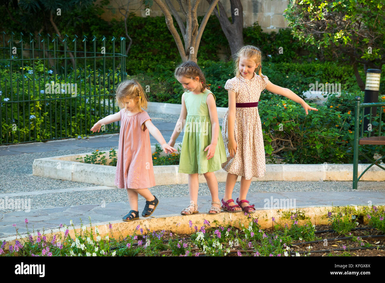 Drei junge Schwestern/Mädchen/Kinder/Kinder/Kind im Alter von 7, 3, & 5 Jahre, auf Familienurlaub Gleichgewicht, Run & Spiel am unteren Barrakka Gardens. Malta Stockfoto