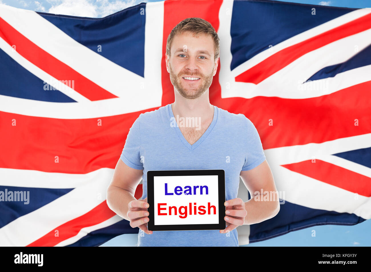 Junger Mann vor der britischen Flagge Holding digital Tablet mit Englisch lernen Text Stockfoto