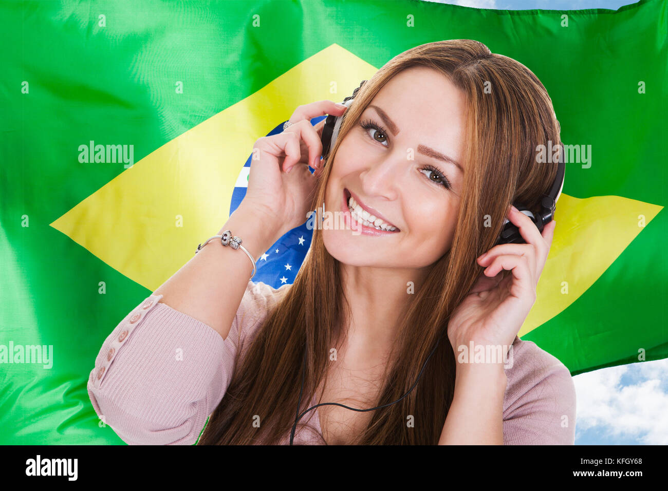 Frau hören Brasilianische Sprache lernen Hörbuch auf Kopfhörer vor der brasilianischen Flagge Stockfoto