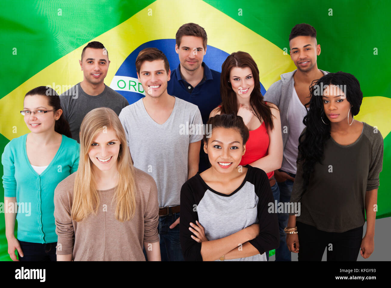 Glückliche multiethnische Gruppe von Menschen, die vor der Flagge Brasiliens stehen Stockfoto