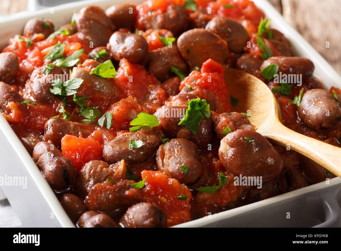 Geschmorte Bohnen in Tomatensoße mit Kräutern und Gewürzen close-up auf dem Tisch. Horizontale Stockfoto