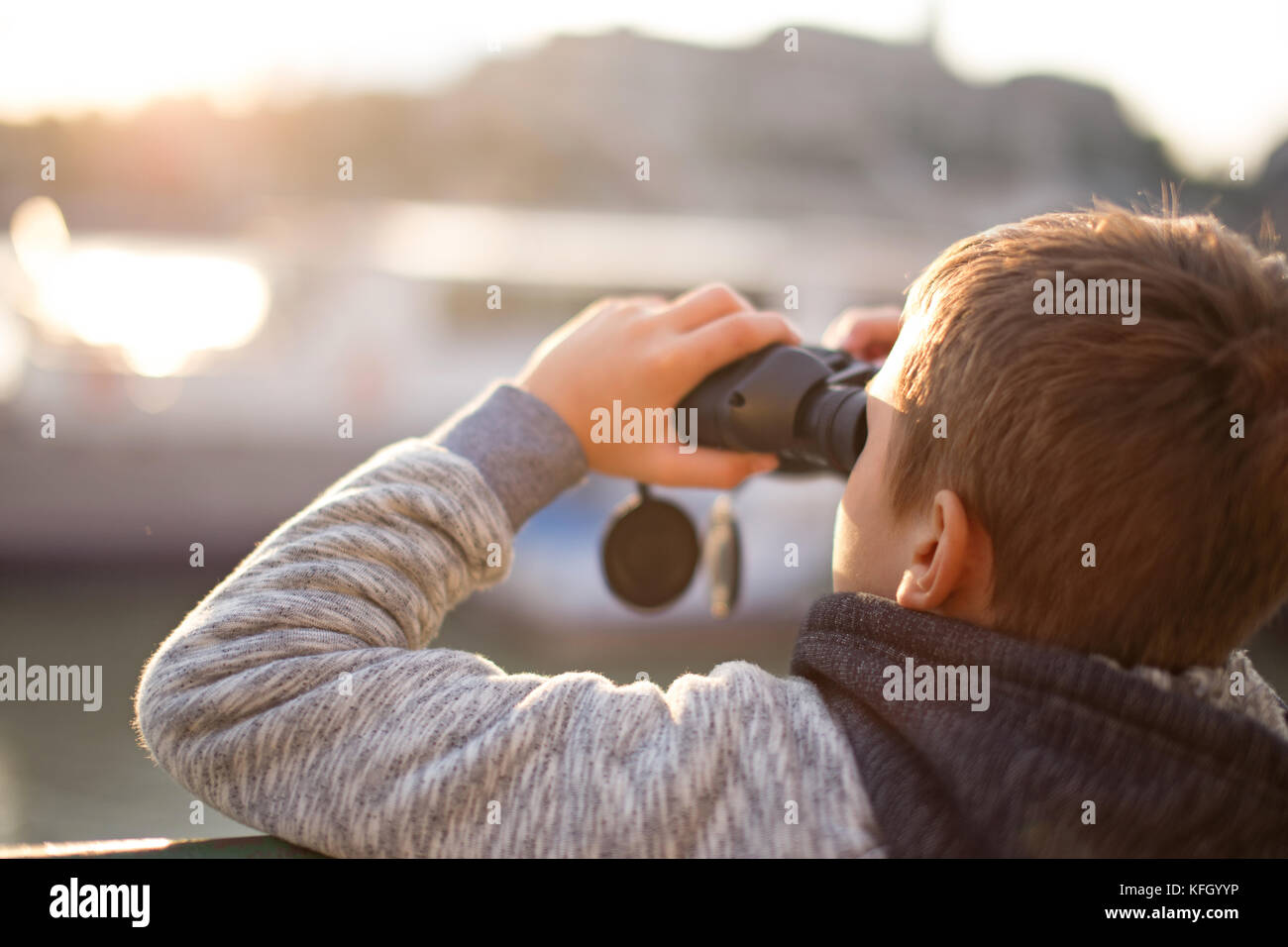 Wenig kaukasischen jungen Beobachten, Suchen, Suche, den Blick durch ein Fernglas im Sonnenuntergang Stockfoto