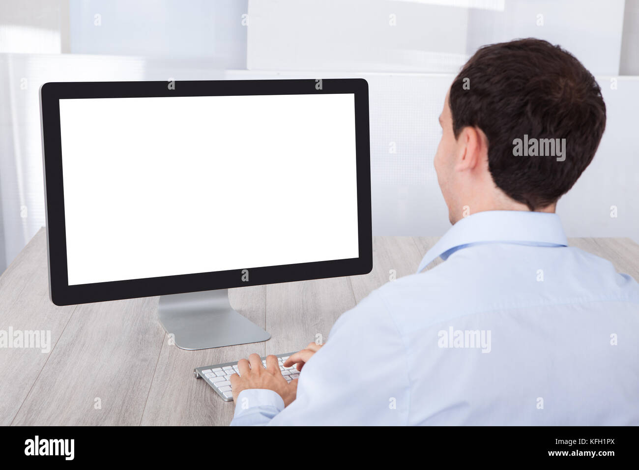 Rückansicht der Geschäftsmann mit Desktop-PC am Schreibtisch im Büro Stockfoto