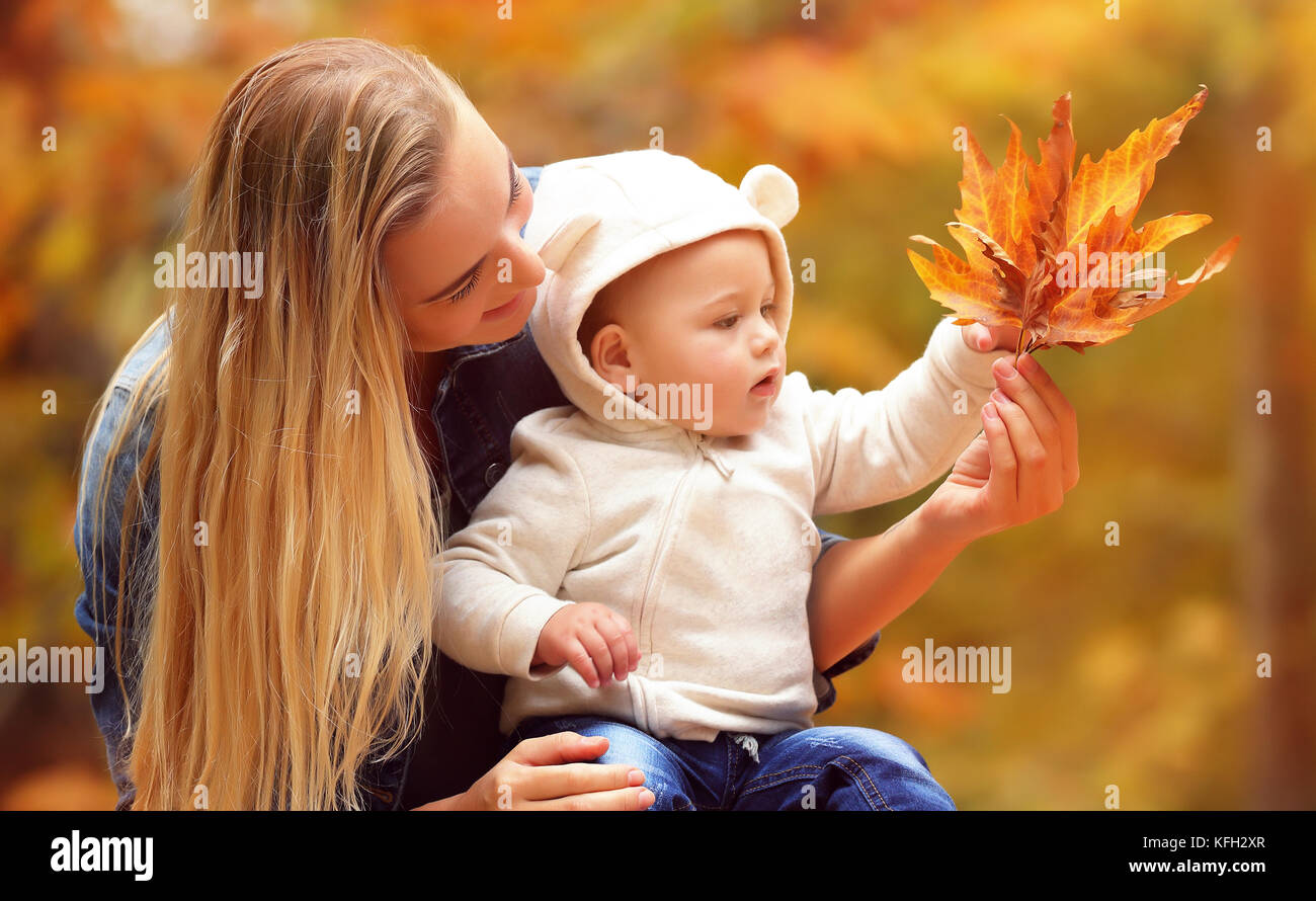 Porträt einer schönen blonden Mutter mit ihrem kleinen Sohn Schönheit des Herbstes Natur, Halten in der Hand trocken orange Ahornblätter, Tag Ausgaben in t Stockfoto