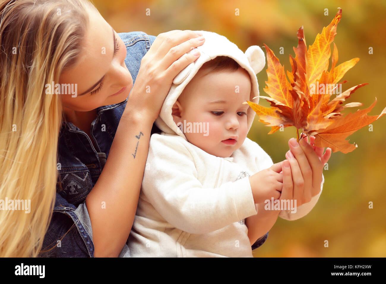 Mutter mit Sohn genießen Herbst, Porträt einer jungen Mutter ihren Sohn suchen, Baby erforscht trockenen Baum Blätter, Leben und Wetter ändern Konzept Stockfoto