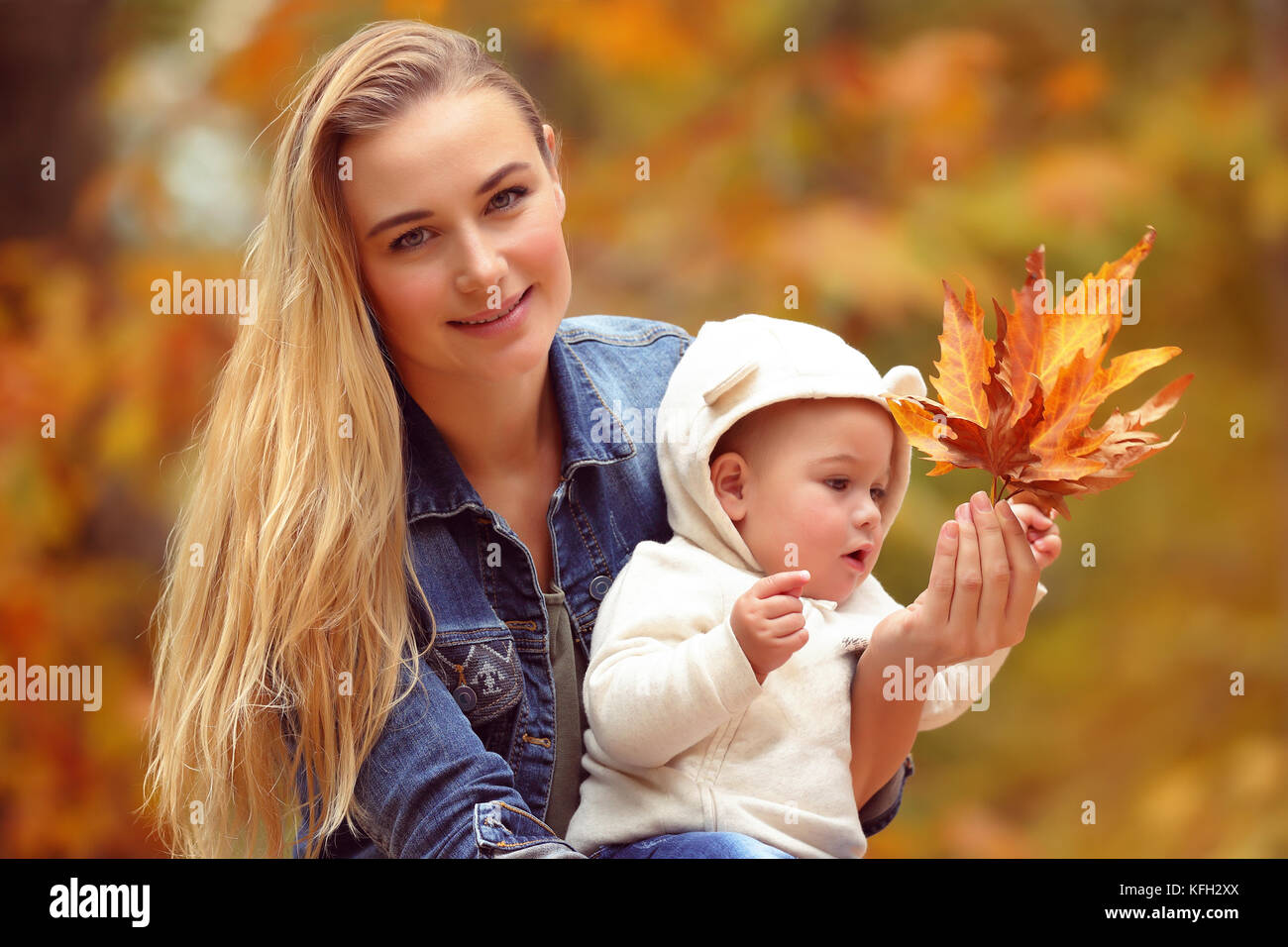 Porträt einer schönen blonden Mutter mit ihrem kleinen Sohn Schönheit der Herbst die Natur in die Hände trocken orange Ahornblätter, Zeit togath Stockfoto