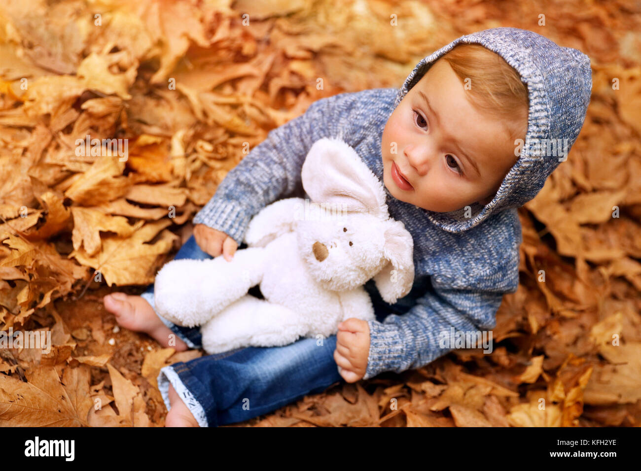 Süße baby boy Spaß im Herbst Park, auf dem Boden sitzend mit trockenen Blättern im Wald bedeckt, wenig Baby spielt mit seinem Spielzeug, glücklich carefre Stockfoto