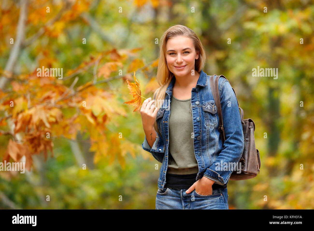 Hübsches blondes Mädchen mit schönen trockenen Maple Leaf in der Hand im Herbst Wald, enjoyng Schönheit von Fallen, Wetter, Wochenende im Park Stockfoto