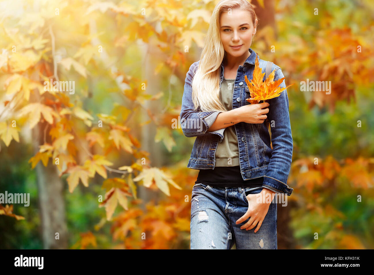 Porträt einer schönen blonden Frau Holding in der Hand schön trocken Gelb maple leaf über herbstliches Laub Hintergrund, Spaß im Herbst Park im Krieg Stockfoto