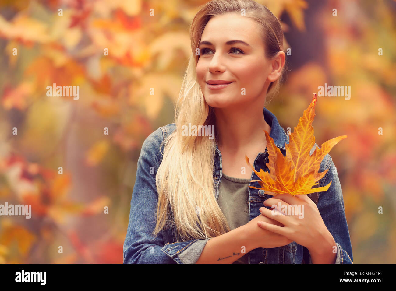 Porträt einer schönen blonden Mädchen mit trockenen Baum Blätter in den Händen verträumter Blick weit, stehend über herbstlaub Hintergrund, genießen Herbstferien ich Stockfoto