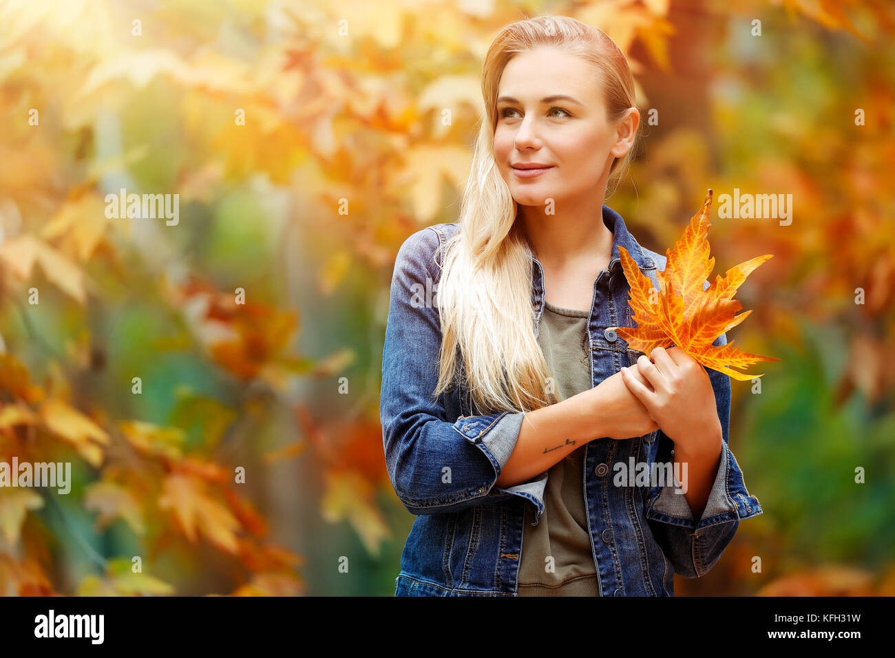 Porträt einer schönen blonden Mädchen mit trockenen Baum Blätter in den Händen verträumt weit suchen, stehen über Fallen, Hintergrund, Herbst Ferien in der pa Stockfoto
