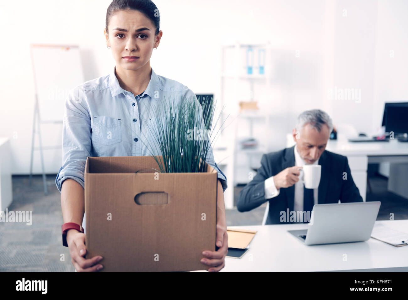 Emotional Brünette mit Box voller Bürobedarf posing erschöpft Stockfoto