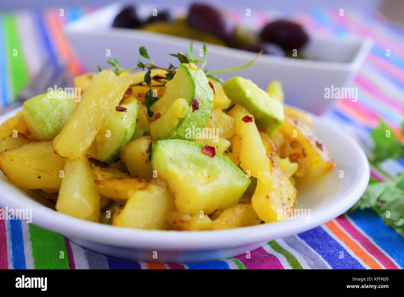 Gebratene Kartoffeln mit Zucchini in Olivenöl, mit eingelegtem Gemüse serviert. Hausmannskost. gesunde Ernährung Konzept Stockfoto