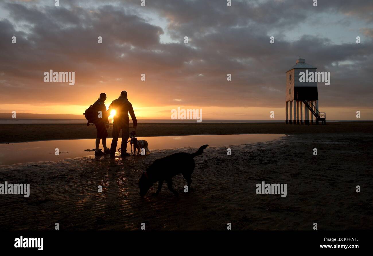 Die Menschen fotografieren den Sonnenuntergang in der Nähe des Leuchtturms in Burnham-on-Sea, Somerset, da die Sonne eine Stunde früher untergeht, nachdem die Uhren letzte Nacht eine Stunde zurückgegangen sind, aufgrund des Endes der Sommerzeit und des Umschalters von der britischen Sommerzeit (BST) zur Greenwich Mean Time (GMT). Stockfoto
