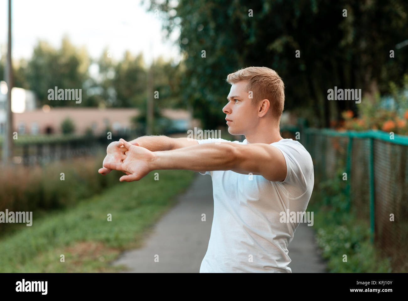 Männliche Athlet warm-up in der Natur, die Straße in der Stadt, bis die Erwärmung der Muskeln der Hände. Im Sommer im Park. Life style. Stockfoto