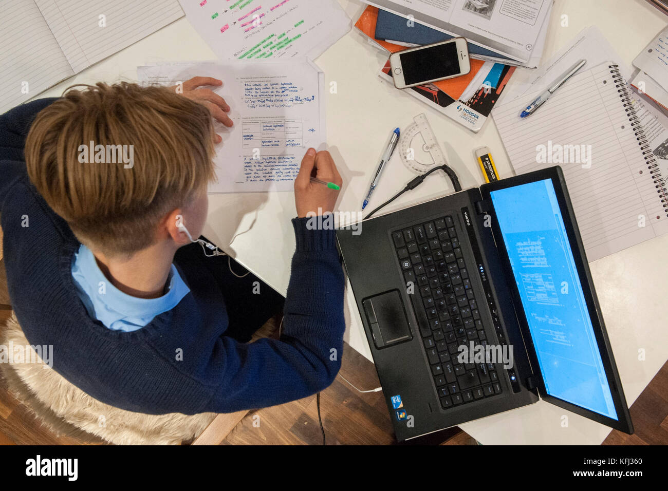 Ein kleiner Junge hat seine Hausaufgaben am Küchentisch in Vorbereitung auf die kommenden Prüfungen Stockfoto