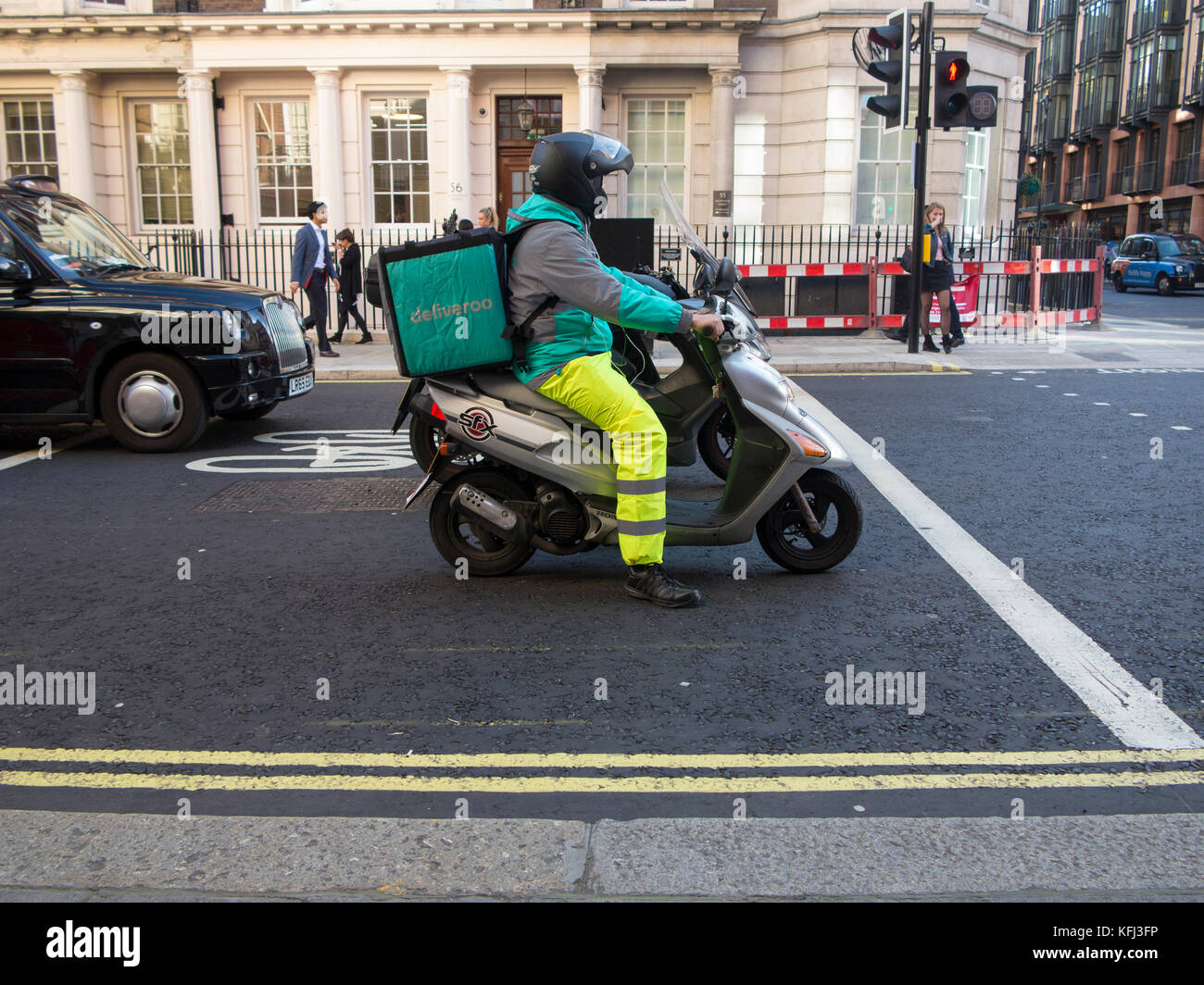 Eine Deliveroo rider liefert einige Essen zum Mitnehmen auf einem Moped Stockfoto