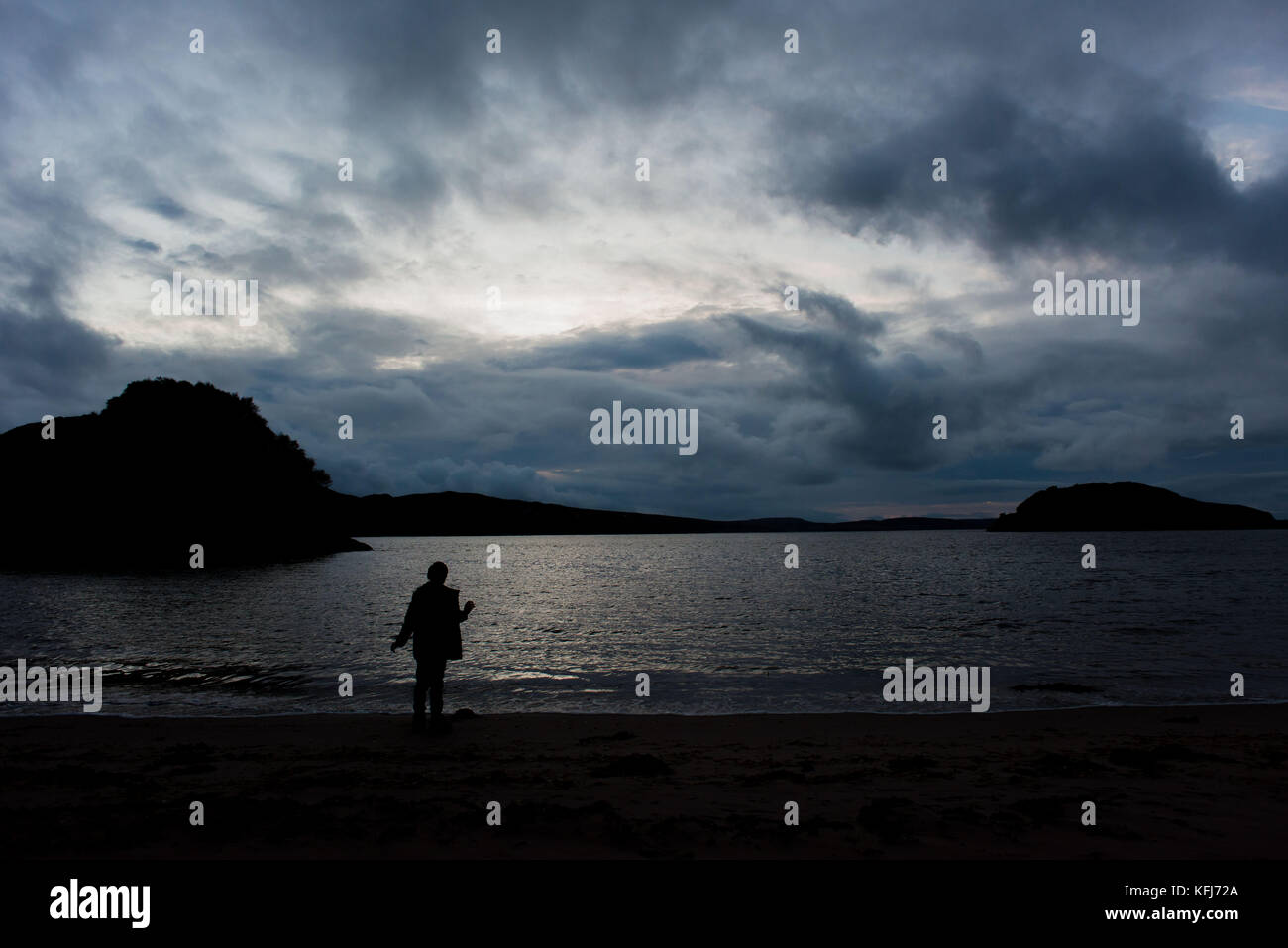 Junge mit Blick auf das Meer bei Sonnenuntergang Stockfoto