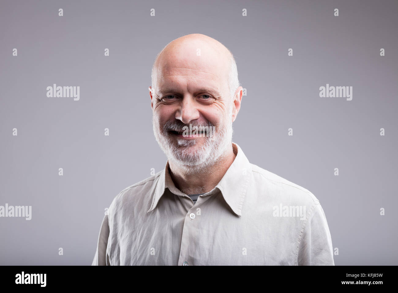 Lächelnd glücklich Kahlen alten Mann Portrait auf einen neutralen grauen Hintergrund Stockfoto