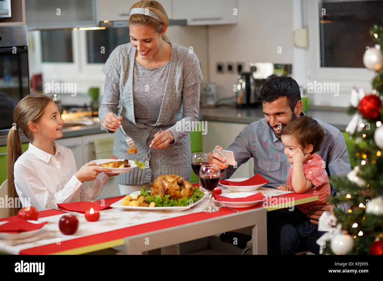 Glückliche Familie mit Kindern am Tisch in Gala Christmas Dinner Stockfoto