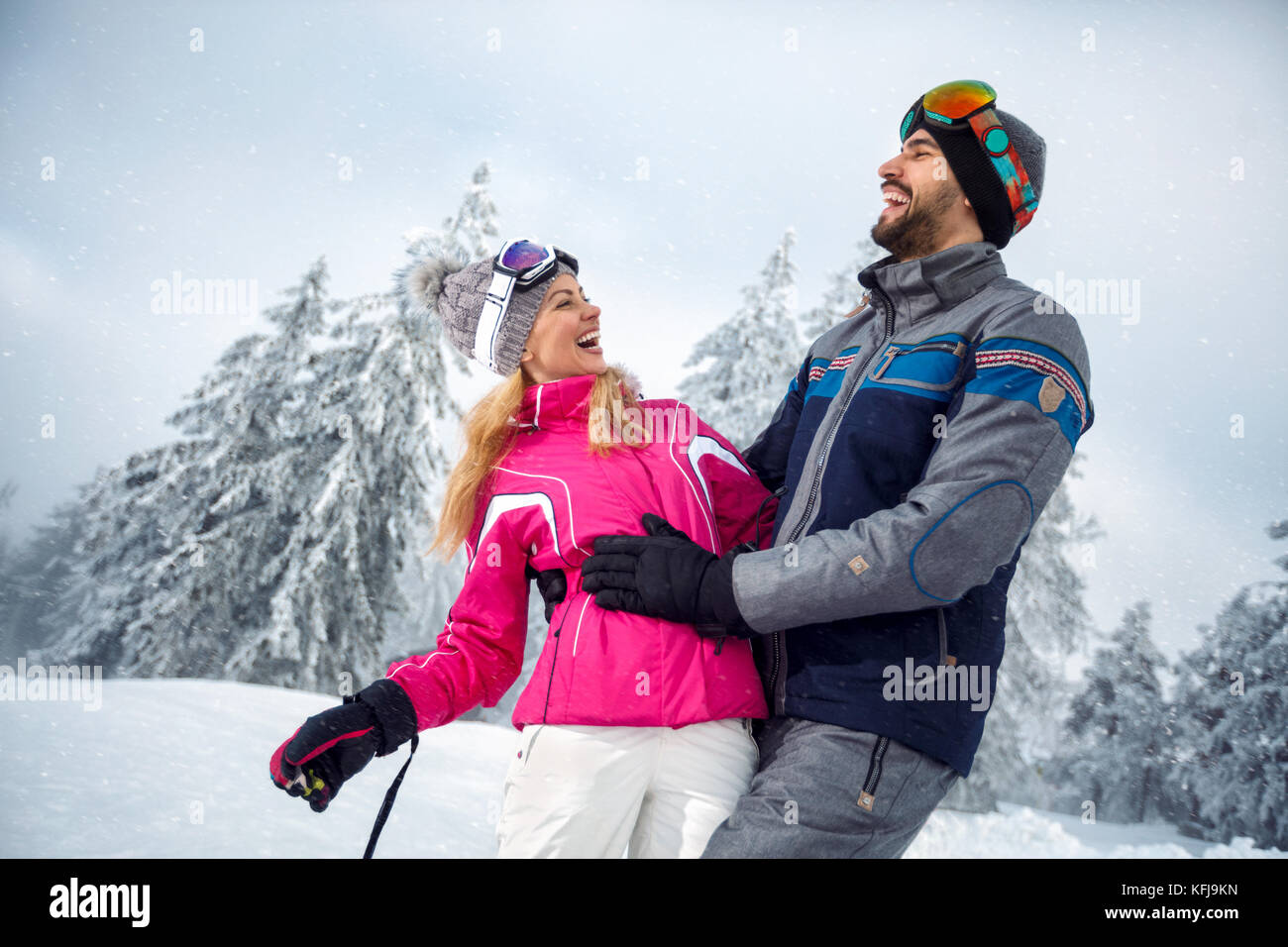 Glückliches junges Paar, das Spaß im Winterurlaub auf dem Berg Stockfoto