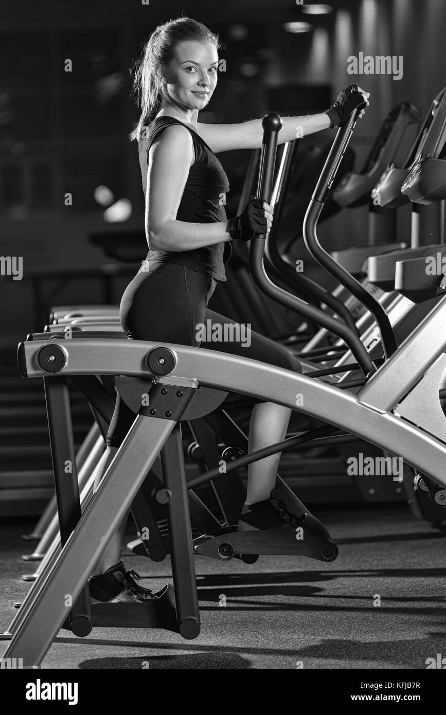 Junge Frau im Fitnessstudio trainieren. Führen Sie an der Maschine. Stockfoto