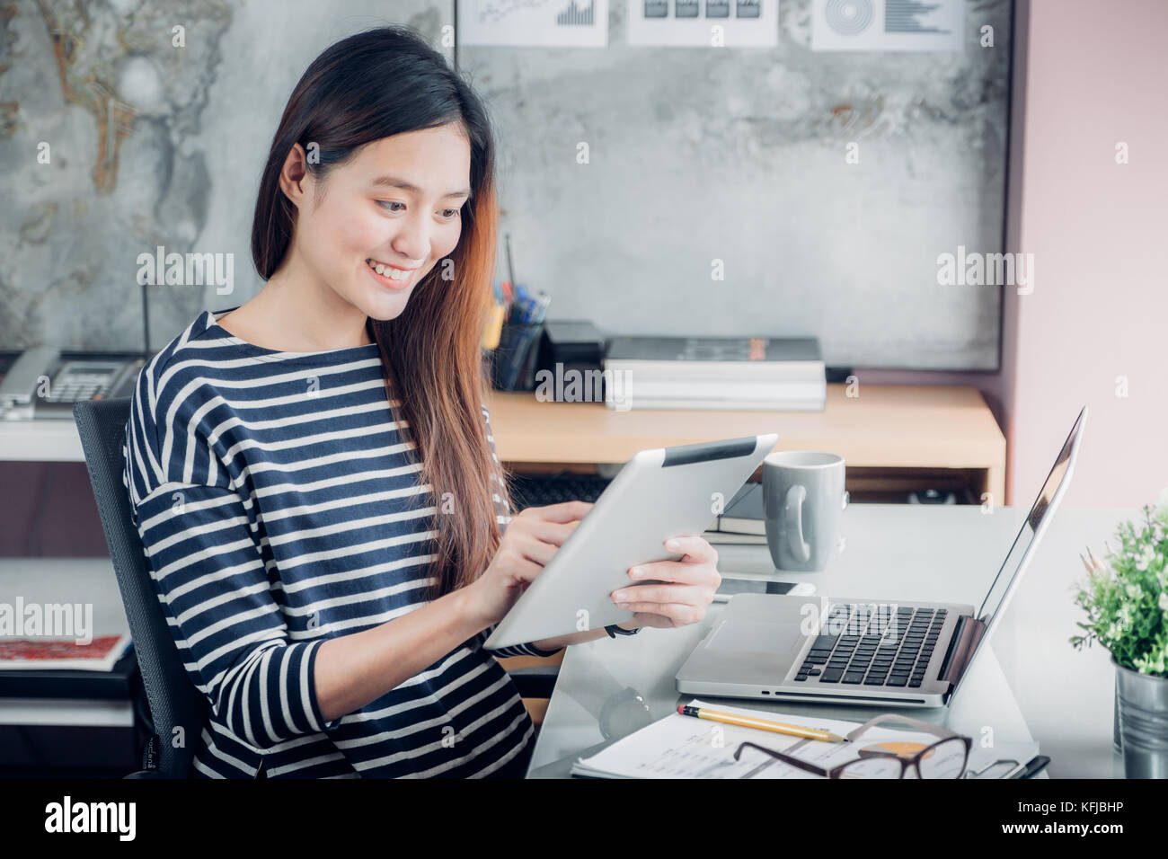 Asiatische Geschäftsfrau mit Tablet vor Laptop im Büro, and Home Office Business Lifestyle Konzept, Einsatz von techno Stockfoto