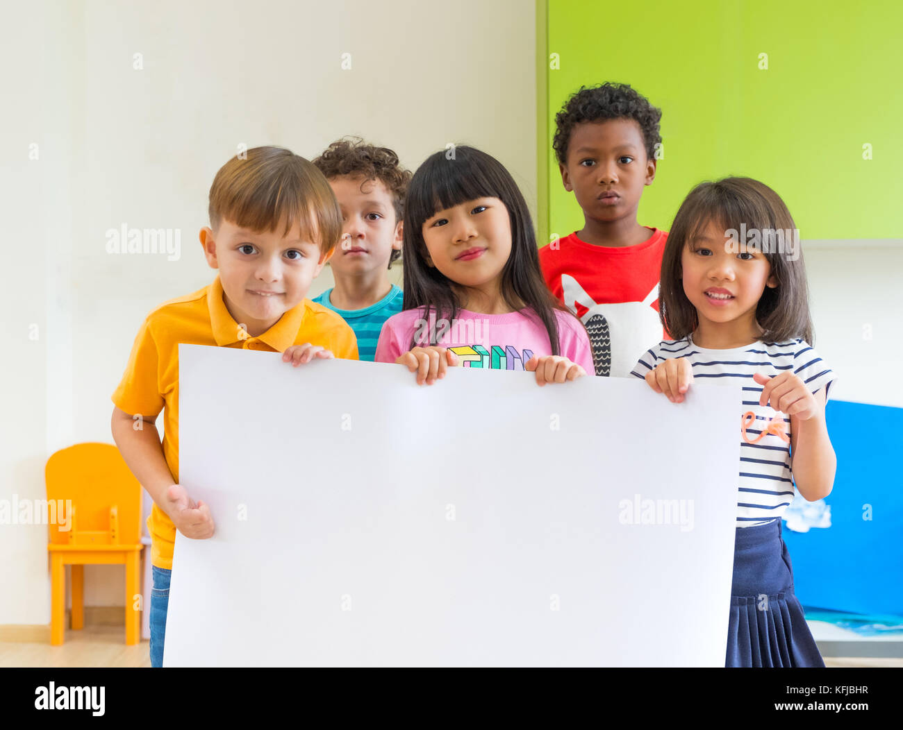 Vielfalt Kinder Holding leeres Plakat im Klassenzimmer an Kindergarten Vorschule, multiethnische Gruppe mit Schild, Mock up für Hinzufügen von Text oder Design. Stockfoto