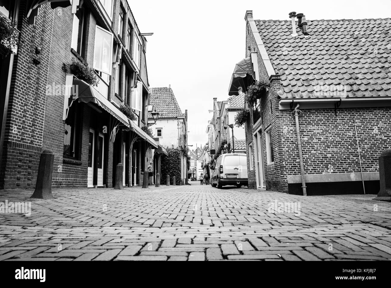 Malerische gemischte Verwendung Straße in der niederländischen Stadt Backsteinbauten, Ziegeldach und gepflasterten Straße Erstellen von Schwarzweiß-Muster in der Architektur. Stockfoto