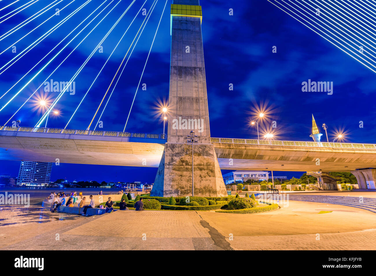 Rama-VIII-Brücke und Riverside Park bei Nacht in Bangkok. Stockfoto