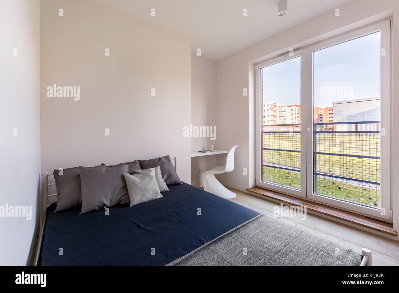 Einfache Schlafzimmer mit kleinem Schreibtisch, Stuhl, Doppelbett und großes Fenster Stockfoto