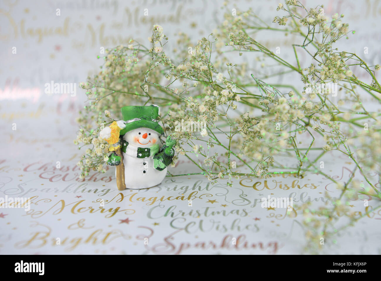 Weihnachten fotografie Bild mit grün weiß xmas glitter Blumen und niedliche Happy snowman Dekoration auf festliche Gold schreiben Geschenkpapier Stockfoto