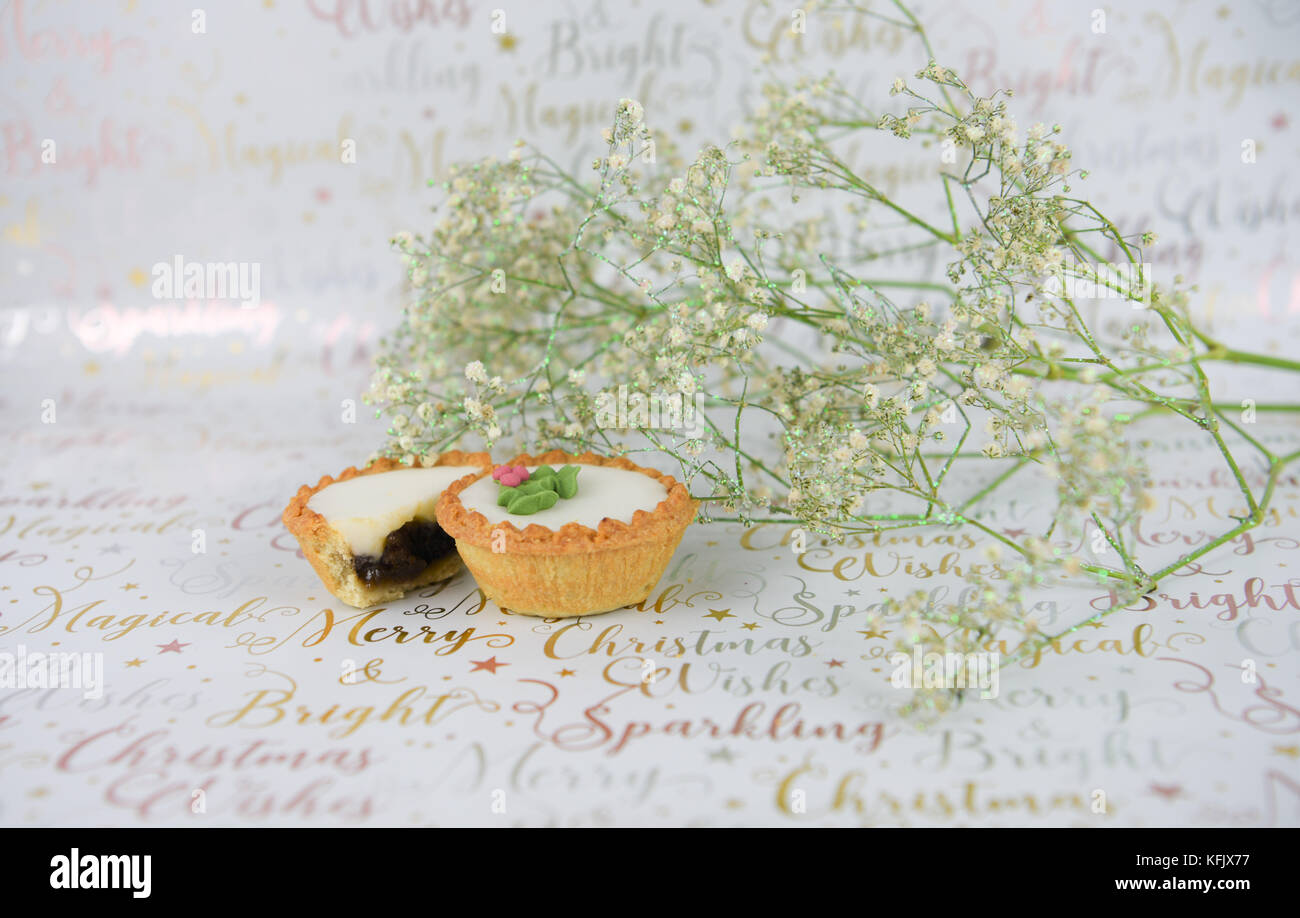 Weihnachten essen Fotografie Bild mit grün weiß xmas glitter Blumen und gefrorener Kuchen mit Holly bei festlichen Gold schreiben Geschenkpapier mince Stockfoto