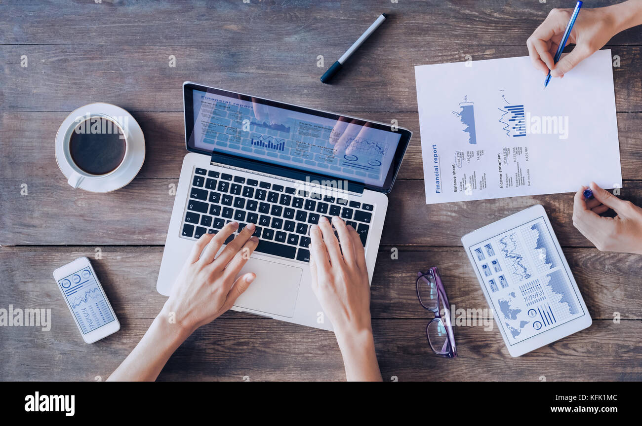 Treffen von Finanzleuten über Berichte und Geschäftsanalysediagramme und Diagramme auf einem digitalen Tablet-Computer, Laptop und Smartphone-Bildschirm auf einem W Stockfoto