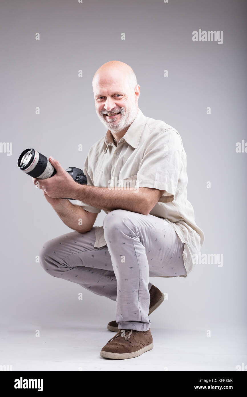 Lächelnd duckte Experte Fotograf seine Kamera in der Hand halten Stockfoto