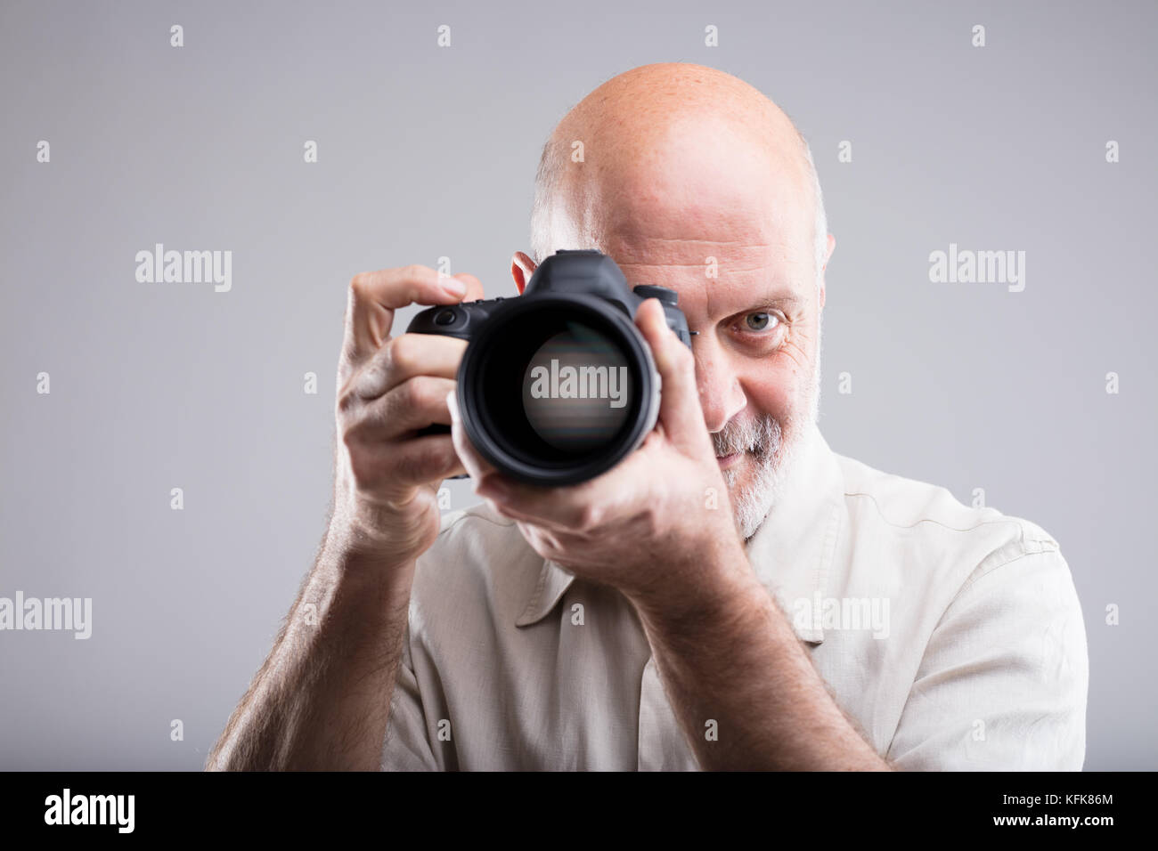 Frontale Porträt eines Senior Fotograf an streben Sie - auf grauem Hintergrund Stockfoto