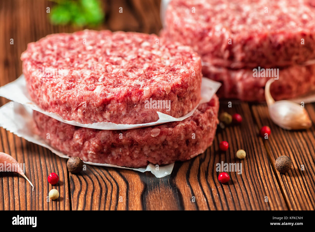 Rohes Rindfleisch Burger Steak, Schnitzel, chemische Pfeffer und Knoblauch auf ländlichen Holz- Hintergrund Stockfoto