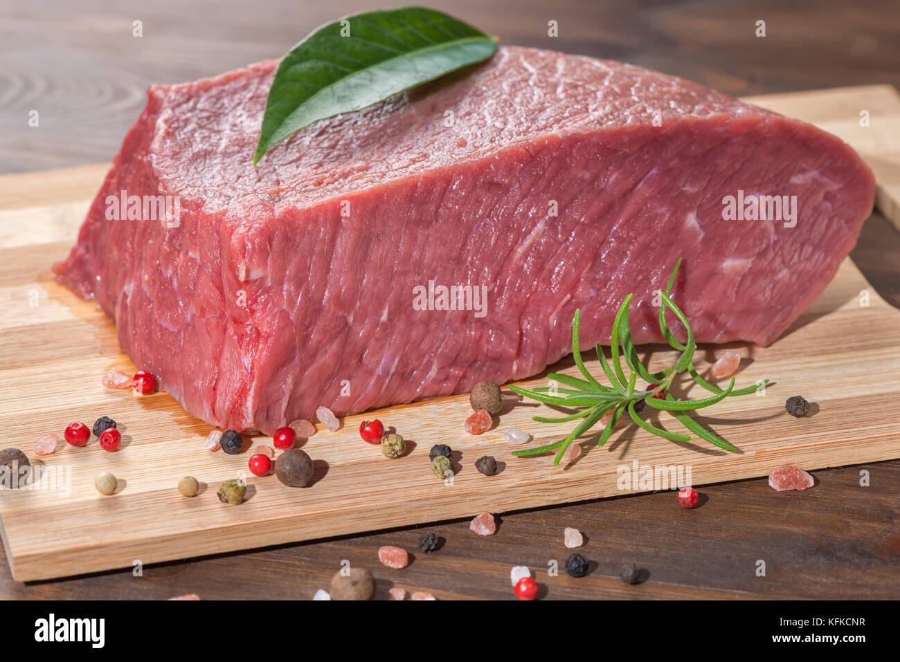 Rohes Rindfleisch ohne Knochen mit Fleisch mit Gewürzen auf Holztisch, Nahaufnahme Stockfoto