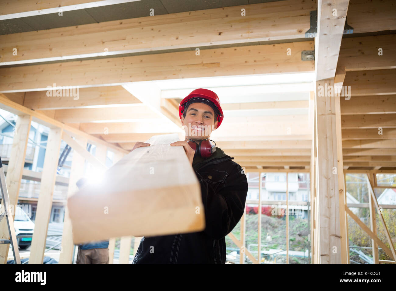 Portrait von Tischler mit Holz auf Schulter auf der Website Stockfoto