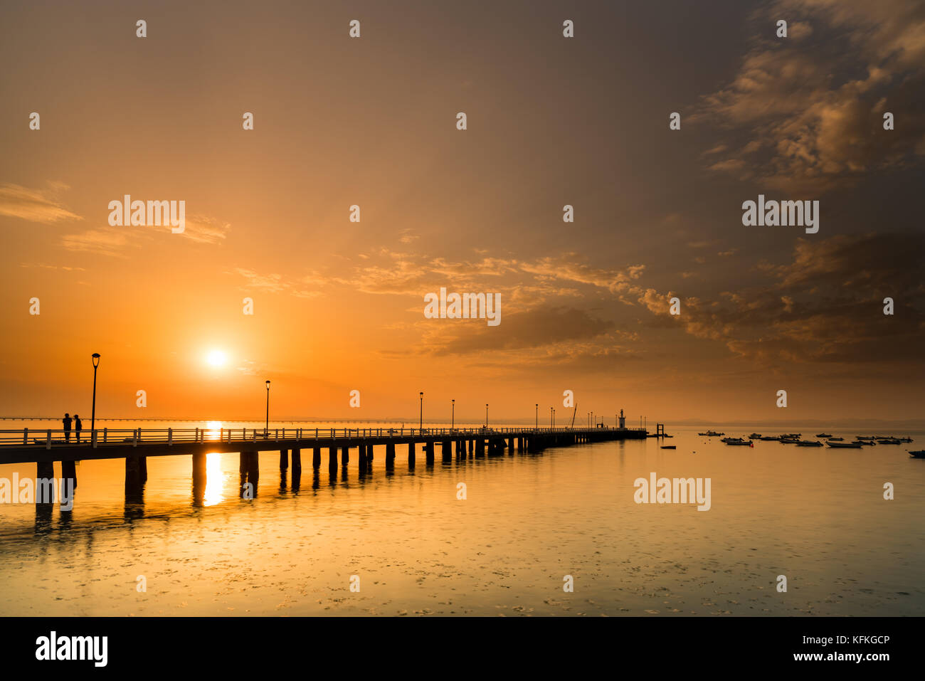 Sonnenuntergang in Alcochete, mit einem Pier bis zum Horizont. Silhouetten von zwei Menschen reden. Stockfoto