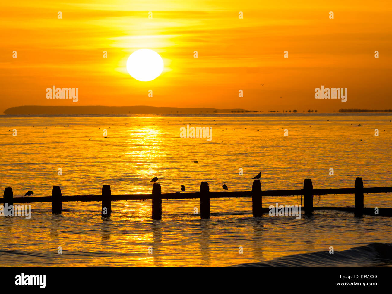 Sonnenuntergang über dem Meer im Herbst in Großbritannien mit der Sonne im Meer widerspiegelt. Stockfoto