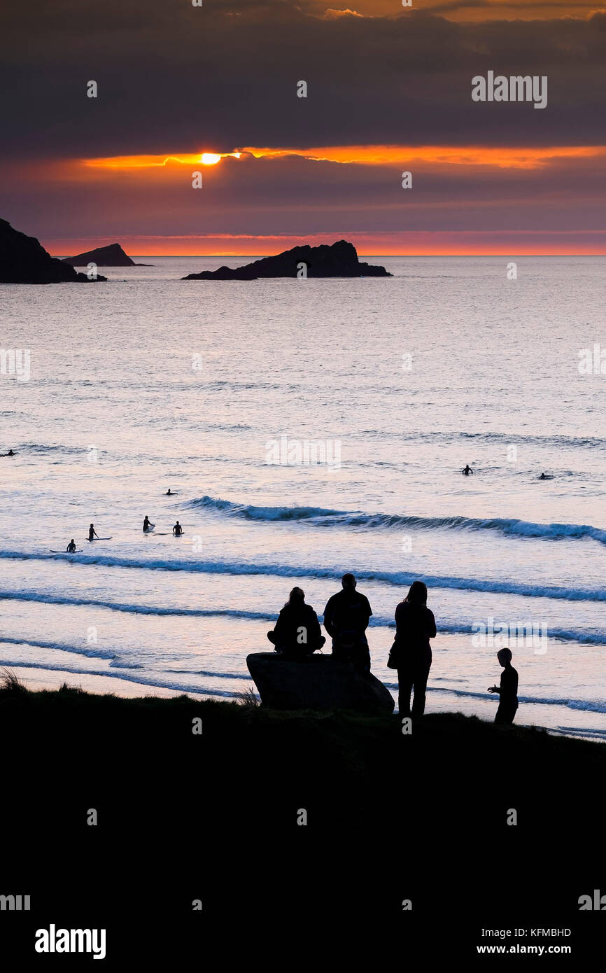 Sonnenuntergang - Menschen in Silhouette gesehen, da sie die Sonne über die Gans und East Watch Pentire Headland in Newquay Cornwall. Stockfoto