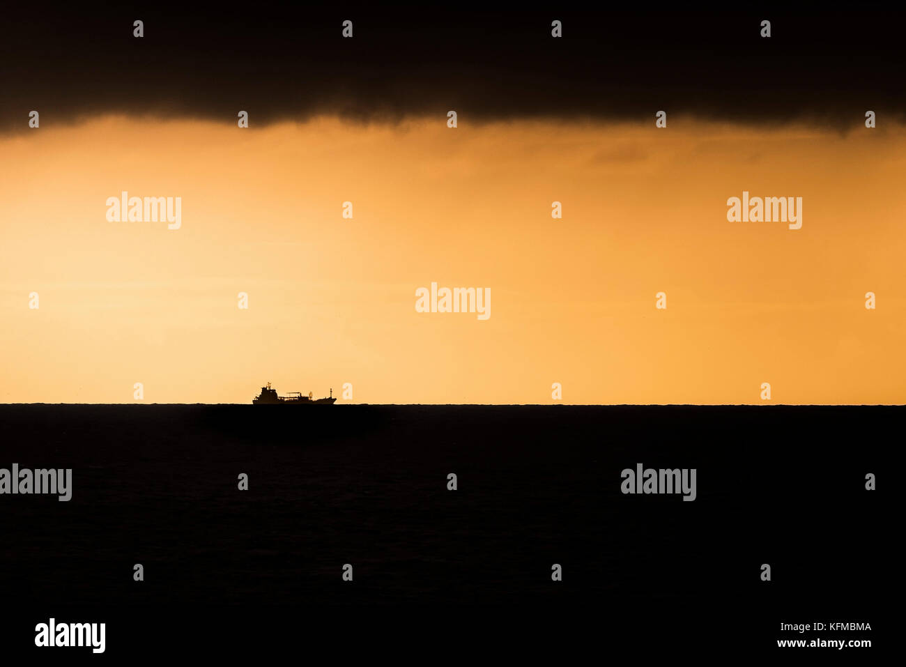 Sonnenuntergang - die Silhouette eines Schiffes gegen den feurigen Sonnenuntergang. Stockfoto