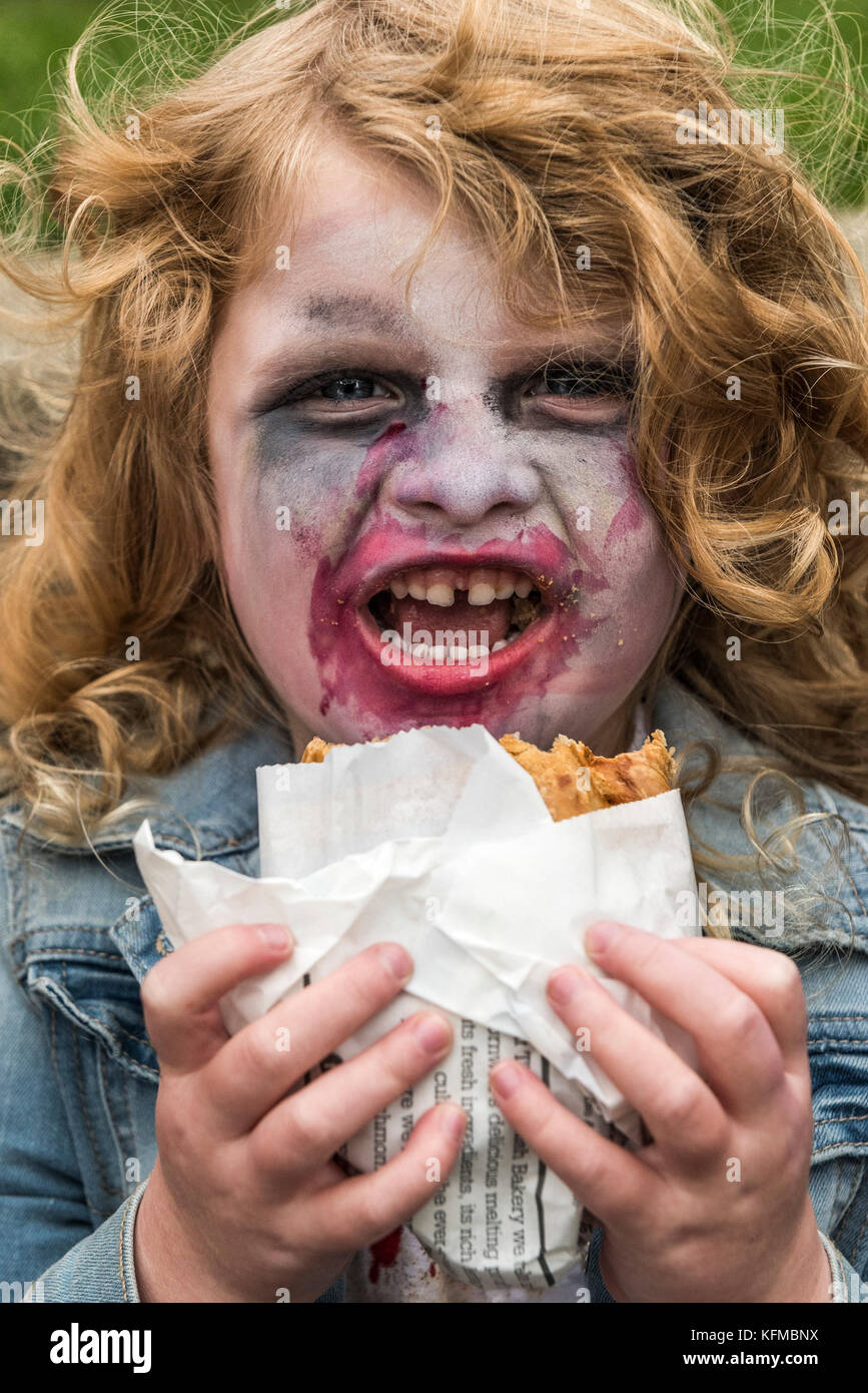 Zombies - ein junger Zombie, der beim jährlichen Zombie Crawl in Newquay, Cornwall, einen kornisch pastösen Fresskai isst. Stockfoto